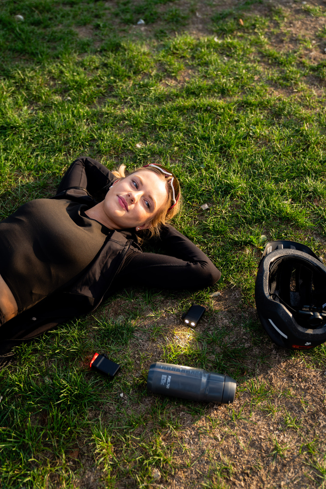 Radfahrerin ruht im Gras neben Helm und KEEP·IT Licht